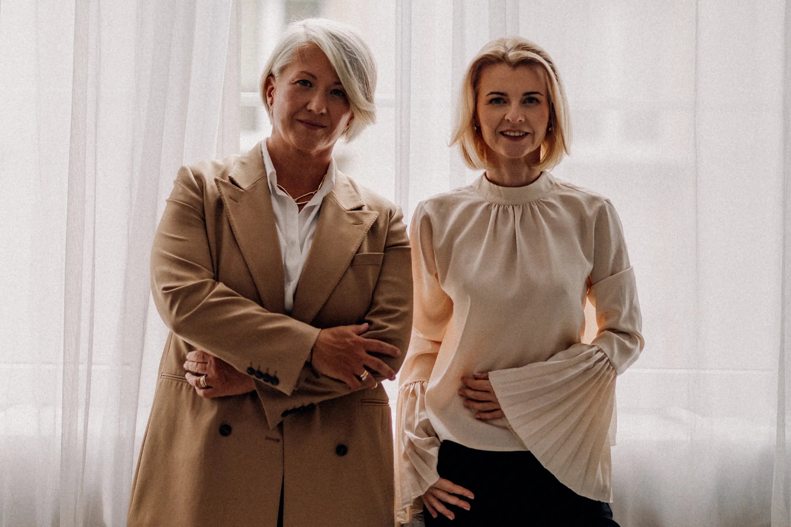 Dwie kobiety w eleganckich stylizacjach – partnerska współpraca i synergia.